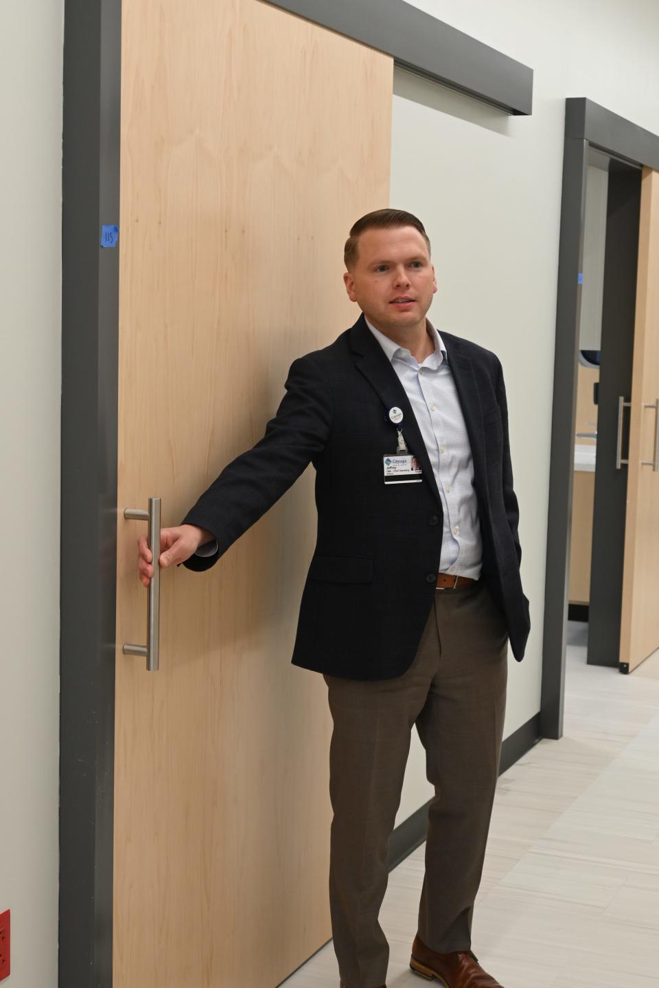 Jeffrey Penoyer, chief operating officer of Cayuga Medical Associates, opens the door to a patient screening room at the Cayuga Park Medical Building .
