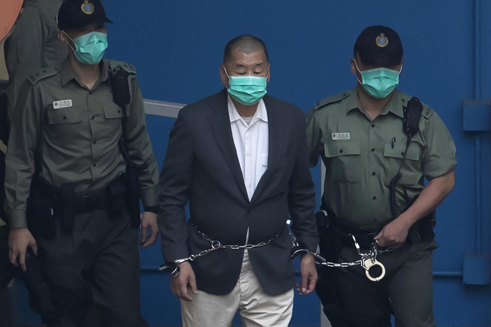 FILE - Jimmy Lai who founded the Apple Daily, is escorted by Correctional Services officers to get on a prison van before appearing in a court in Hong Kong, Dec. 12, 2020. Lai broke into the media industry about 30 years ago armed with the belief that delivering information equates with delivering freedom. Lai now is accused of endangering national security with his now-defunct pro-democracy newspaper Apple Daily. (AP Photo/Kin Cheung, File)