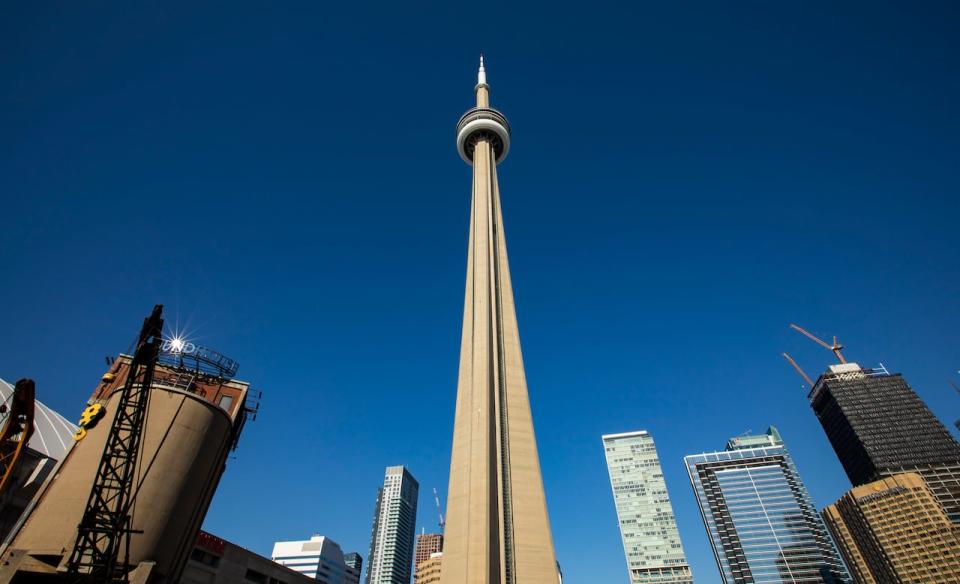 View of the CN Tower from Roundhouse Park - November 10, 2022. See tower, skyline and clear blue sky.