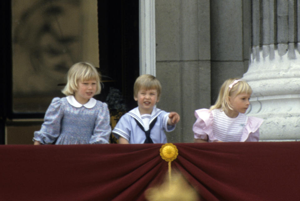 LONDON, ENGLAND - JUNE 15:  Prince William points from the balcony of Buckingham Place with his cousin Zara Phillips (L) and Lady Davina Windsor (R) following Trooping the Colour on June 15, 1985 in London, England. (Photo by Anwar Hussein/Getty Images)