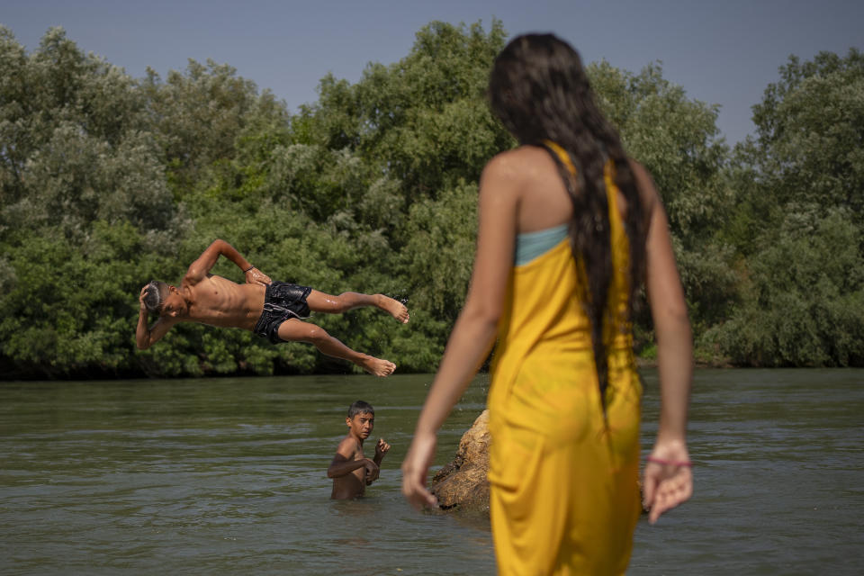 Youngsters cool off in the river Arges, outside Bucharest, Romania, Wednesday, July 12, 2023. Weather services issued a heat warning for the coming days in southern Romania, with temperatures expected to exceed 40 degrees Centigrade (104 Fahrenheit) in the shade. (AP Photo/Vadim Ghirda)