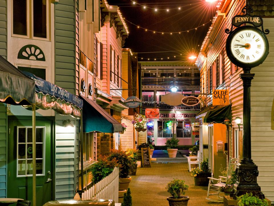 a small street in rehonoth beach lined with shops and string lights