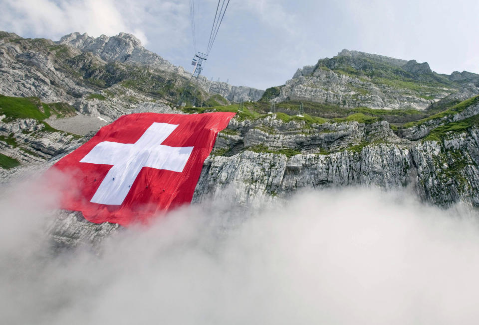 File---Picture taken July 31, 2009 shows the world largest Swiss flag hanging at the rock face of the mountain Saentis in Schwaegalp, Switzerland, The flag measures 120 meters square and is believed to be the world second largest flag. Tomorrow Aug. 1, Switzerland is celebrating the national holiday. (Ennio Leanza/Keystone via AP)