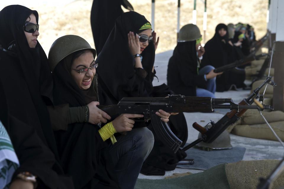 In this Thursday, Aug. 22, 2013 photo, a female member of the Basij paramilitary militia aims her rifle as a trainer assists her during a training session in Tehran, Iran. With a presence in nearly every city and town across Iran, the paramilitary Basij volunteer corps has an ever-increasing influence on life in the Islamic Republic. (AP Photo/Ebrahim Noroozi)