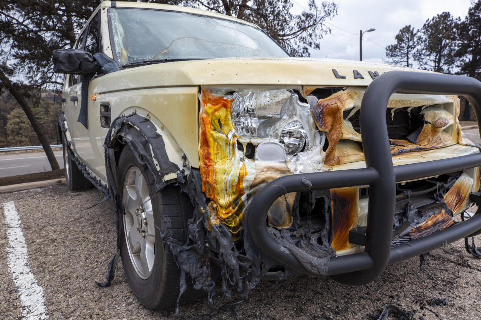 The partially melted body of a car sits in the parking lot of the Swiss Chalet Hotel after it was destroyed by the South Fork Fire in the mountain village of Ruidoso, N.M., Saturday, June 22, 2024. (AP Photo/Andres Leighton)