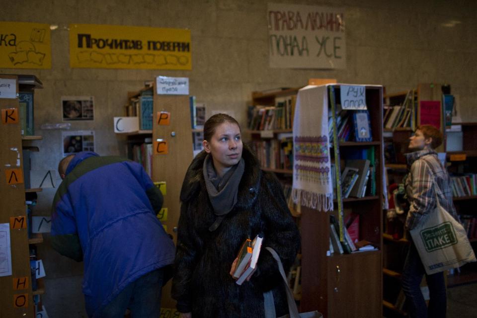 In this photo taken on Thursday, Feb. 6, 2014, Ukrainian protesters choose books organized on shelves in an improvised library set inside the Ukrainian House in Kiev. When the fervor flags for the protesters in Ukraine’s capital and they want to get away from the barricades for a little while, many of them are heading to an improvised library in one of the buildings seized by demonstrators. (AP Photo/Emilio Morenatti)