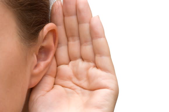 Closeup of a person's hand cupped over their ear