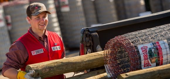 Tractor Supply Company employee smiling and moving fencing materials.