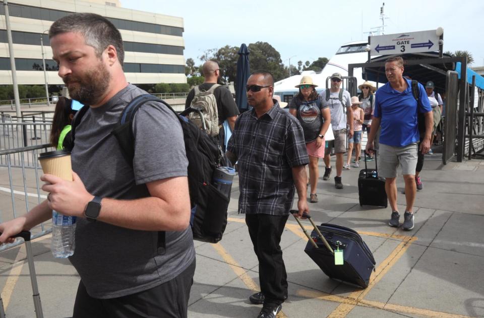 People walk off a ferry with luggage.