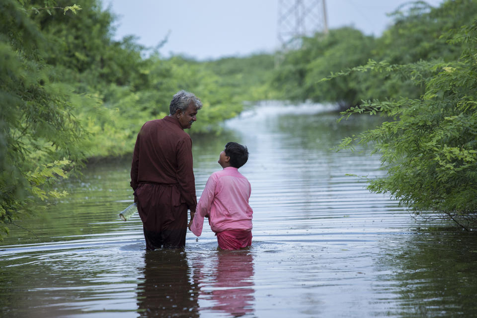 Abdul Jabbar and his son Muhammad Hashim walk across floodwater. Their home was devastated during the monsoon floodsSaiyna Bashir/Arete/WFP