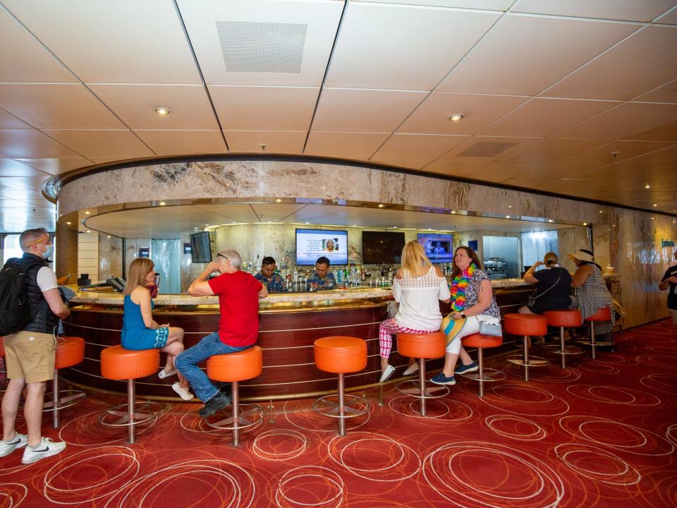 People sitting at a curved bar as bartenders prepare drinks.