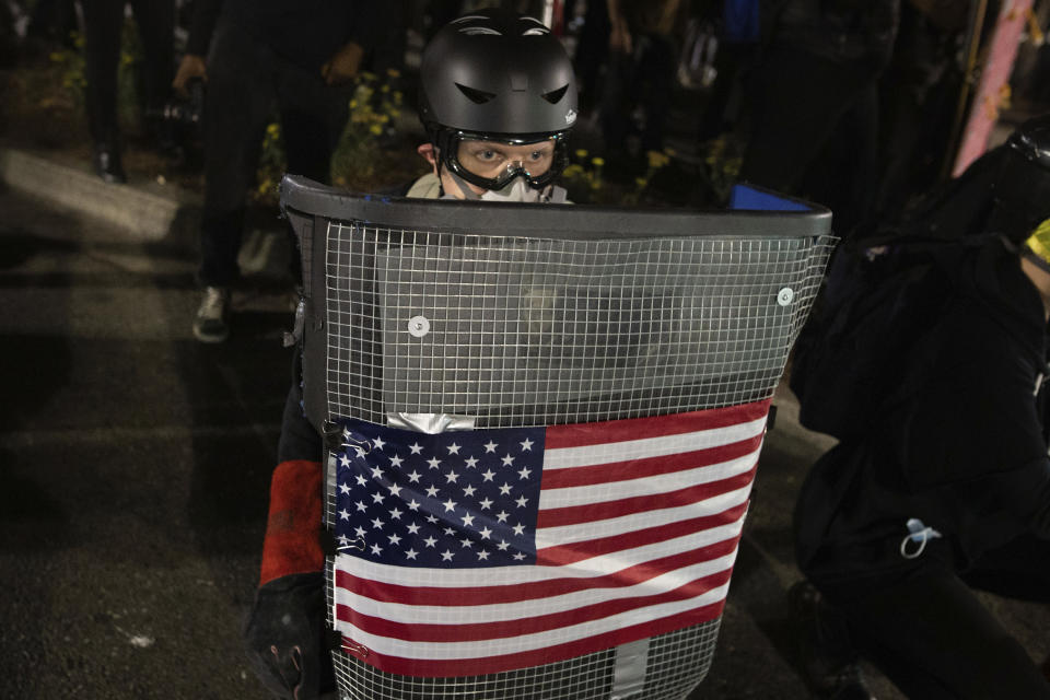 A protester holds a homemade riot shield during a protest in front of the Oakland Police Department Station on Saturday, July 25, 2020, in Oakland, Calif. Protesters in California set fire to a courthouse, damaged a police station and assaulted officers after a peaceful demonstration intensified late Saturday, Oakland police said. (AP Photo/Christian Monterrosa)