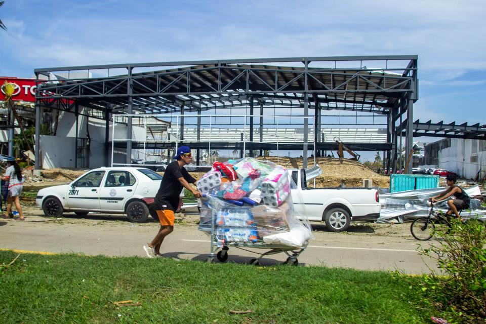 A person walks carrying goods from a looted store after hurricane Otis (Getty Images)