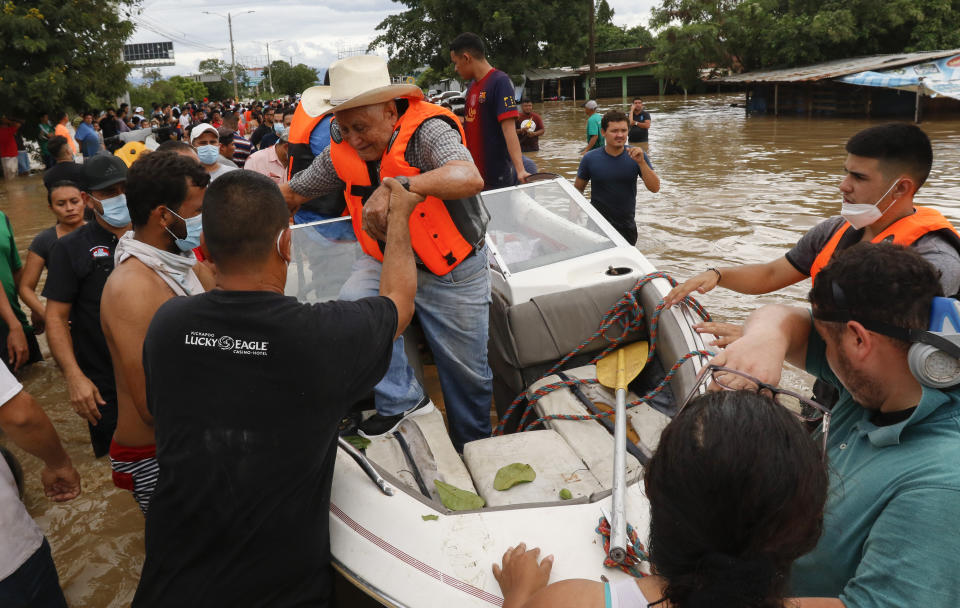 A resident is helped off a boat after he was rescued from a flooded area in the neighborhood of Planeta, Honduras, Thursday, Nov. 5, 2020. The storm that hit Nicaragua as a Category 4 hurricane on Tuesday had become more of a vast tropical rainstorm, but it was advancing so slowly and dumping so much rain that much of Central America remained on high alert. (AP Photo/Delmer Martinez)