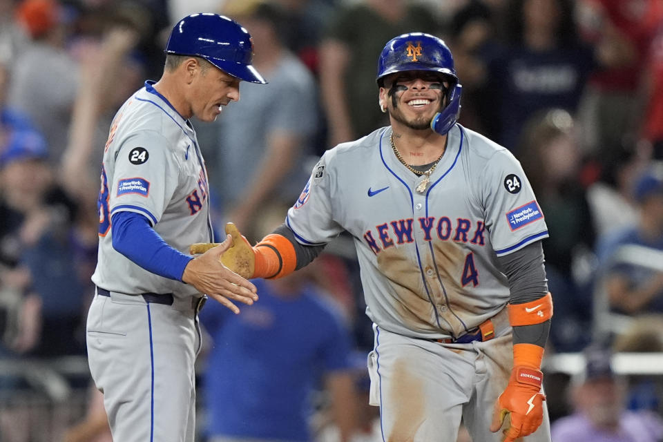 New York Mets' Francisco Alvarez (4), right, is congratulated by bench coach John Gibbons, left, after hitting a triple during the 10th inning of a baseball game against the Washington Nationals at Nationals Park, Monday, July 1, 2024, in Washington. (AP Photo/Mark Schiefelbein)