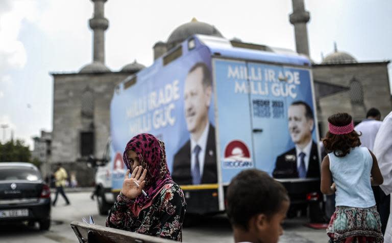 A Syrian refugee girl gestures in front of a truck with a campaign poster of Turkish presidential candidate Recep Tayyip Erdogan near a mosque in Istanbul, on August 8, 2014