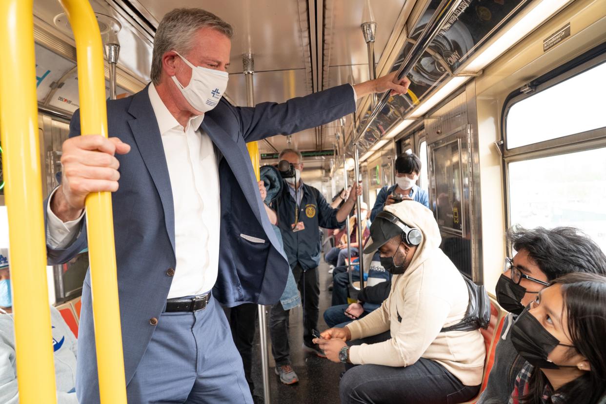 A masked Mayor de Blasio talks to two straphangers on the No. 6 train in the Bronx.