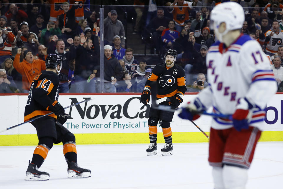 Philadelphia Flyers' Claude Giroux (28) and Sean Couturier (14) celebrate past New York Rangers' Jesper Fast (17) after Giroux's goal during the second period of an NHL hockey game, Friday, Feb. 28, 2020, in Philadelphia. (AP Photo/Matt Slocum)