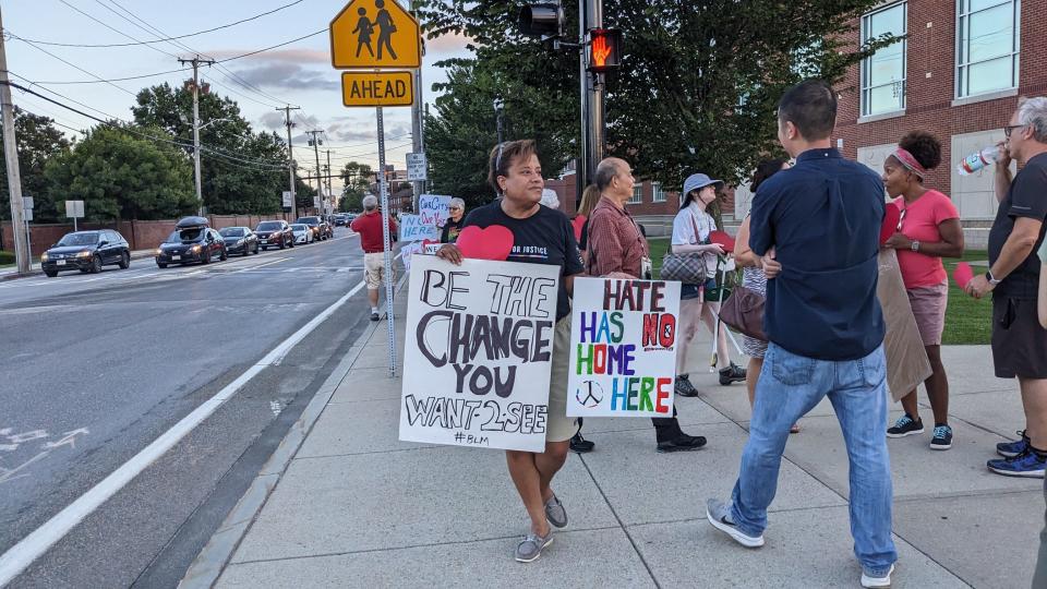 People hold signs in front of Central Middle School in Quincy before a meeting about the temporary shelter for homeless families housed on the campus of Eastern Nazarene College.