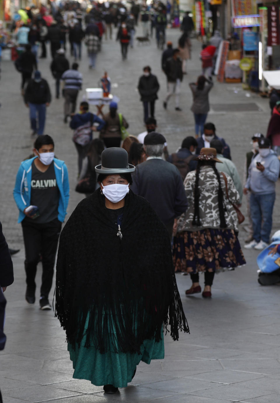 Pedestrians wearing face masks amid the new coronavirus pandemic walk in La Paz, Bolivia, Monday, June 1, 2020. After more than two months of quarantine the government approved the reopening of some commercial activity and public transport, as the total lockdown begins to ease,. (AP Photo/Juan Karita)