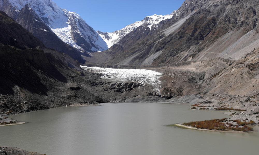 lake pools in front of the Darkut glacier – grey expanse of water between snow-covered mountain slopes with glacier seen through valley