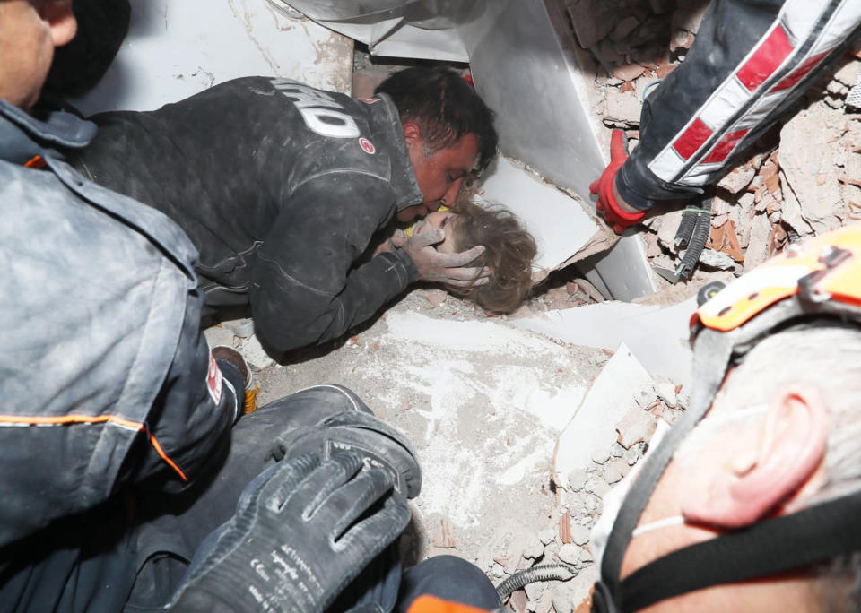 In this photo provided by the government's Search and Rescue agency AFAD, rescue workers, who were trying to reach survivors in the rubble of a collapsed building, surround Ayda Gezgin in the Turkish coastal city of Izmir, Turkey, Tuesday, Nov. 3, 2020, as they pull the young girl out alive from the rubble of a collapsed apartment building four days after a strong earthquake hit Turkey and Greece. The girl, Ayda Gezgin, was seen being taken into an ambulance on Tuesday, wrapped in a thermal blanket, amid the sound of cheers and applause from rescue workers. (AFAD via AP)