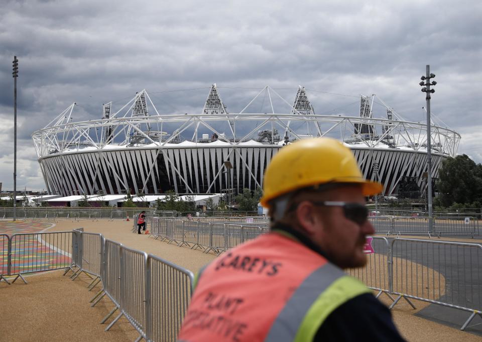 A construction worker stands outside the Olympic Stadium as preparations continue for the 2012 Summer Olympics, Sunday, July 15, 2012, in London. (AP Photo/Jae Hong)