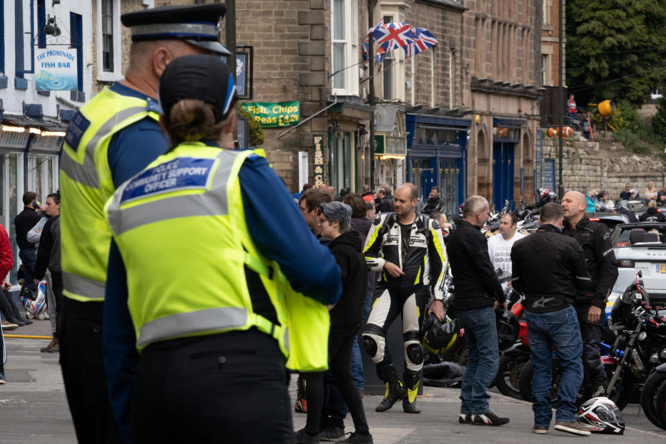 Police look on at a crowd gathered in the village. (Tom Maddick / SWNS)