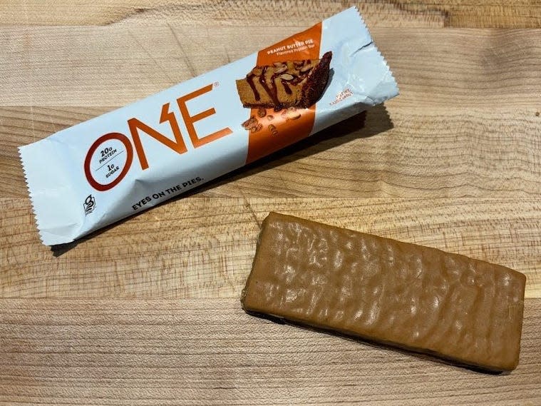 One protein bar wrapper with unwrapped bar next to it 