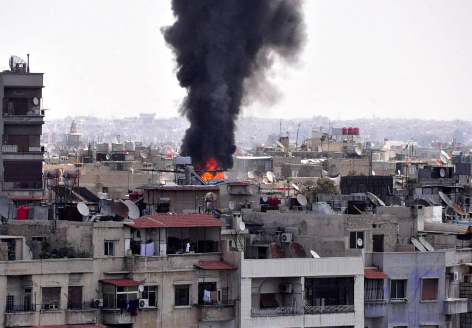 In this photo released by the Syrian official news agency SANA, black smoke and flame rise from the rooftop of a building that was, according to SANA, attacked by a mortar shelled by the Syrian rebels in Damascus, Syria, Saturday April 5, 2014. Al-Qaida's leader, Ayman al-Zawahri, called on fighters to determine who killed his chief representative in Syria, a man many militant groups believe died at the hands of a rival militia, in a move that highlighted a conflict between rebels that has killed hundreds. (AP Photo/SANA)