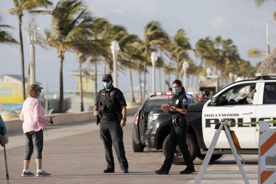 FILE - In this May 13 2020 file photo, Hollywood police officers monitor activity along the Hollywood Beach Broadwalk during the new coronavirus pandemic in Hollywood, Fla. In state after state, the local health departments charged with doing the detective work of running down the contacts of coronavirus patients are falling well short of the number of people needed to do the job. (AP Photo/Lynne Sladky, File)