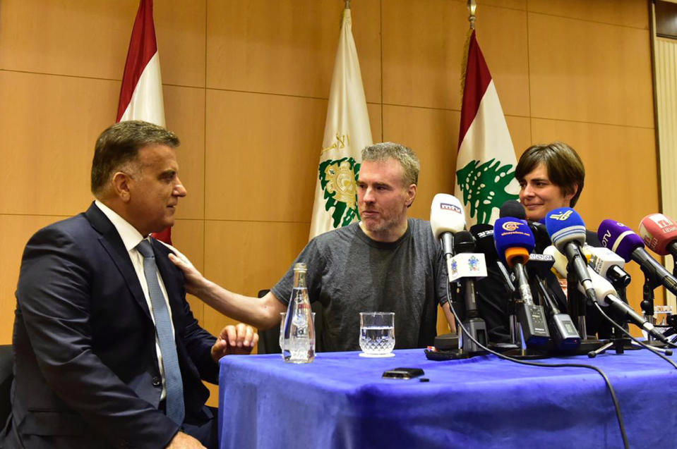 This handout photo by the Lebanese General Security Directorate, shows Maj. Gen. Abbas Ibrahim, left, Lebanon's General Security Chief, speaks with Canadian citizen Kristian Lee Baxter, center, who was released from Syrian prisons to Lebanon, during a press conference in Beirut, Lebanon, Friday, Aug 9, 2019. Baxter held in Syrian prisons since last year and freed after Lebanese mediation said Friday he had no idea if anyone knew he was still alive. The Lebanese general who mediated his release said Baxter was heading home. It was not clear when Baxter was released from Syria. (The Lebanese General Security Directorate via AP)