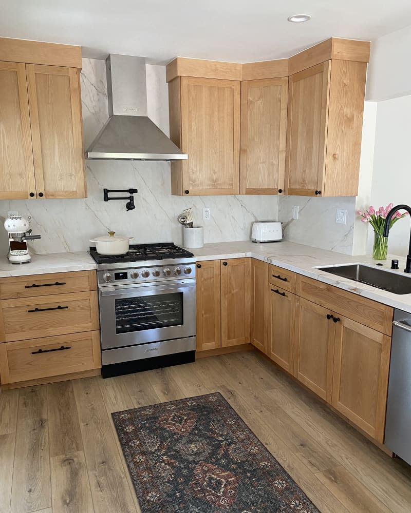 white kitchen with wood cabinets and marble counter and backsplash after makeover