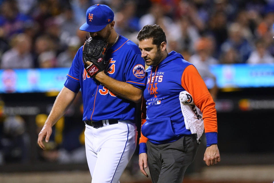 New York Mets starting pitcher Tylor Megill, left, talks to a trainer as he leaves during the fourth inning of the team's baseball game against the Milwaukee Brewers on Thursday, June 16, 2022, in New York. (AP Photo/Frank Franklin II)