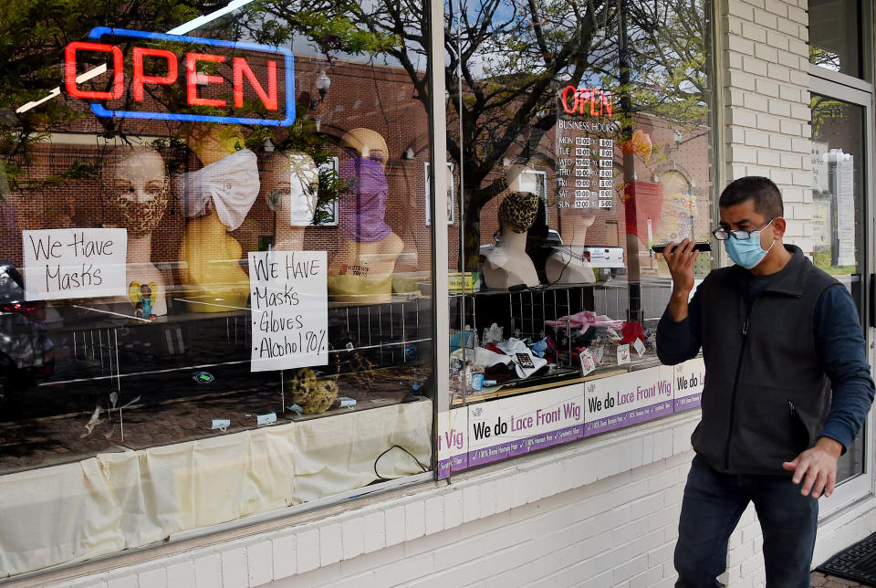 A man walks past mannequin heads wearing masks in the window of a small boutique advertising availability of masks, gloves, and other pandemic necessities amid the Coronavirus outbreak in Arlington, Virginia, on April 27, 2020. - Several states have seen protests against stay-at-home orders and Georgia has allowed thousands of businesses to resume operations, against the advice of health experts. (Photo by Olivier DOULIERY / AFP) (Photo by OLIVIER DOULIERY/AFP via Getty Images)