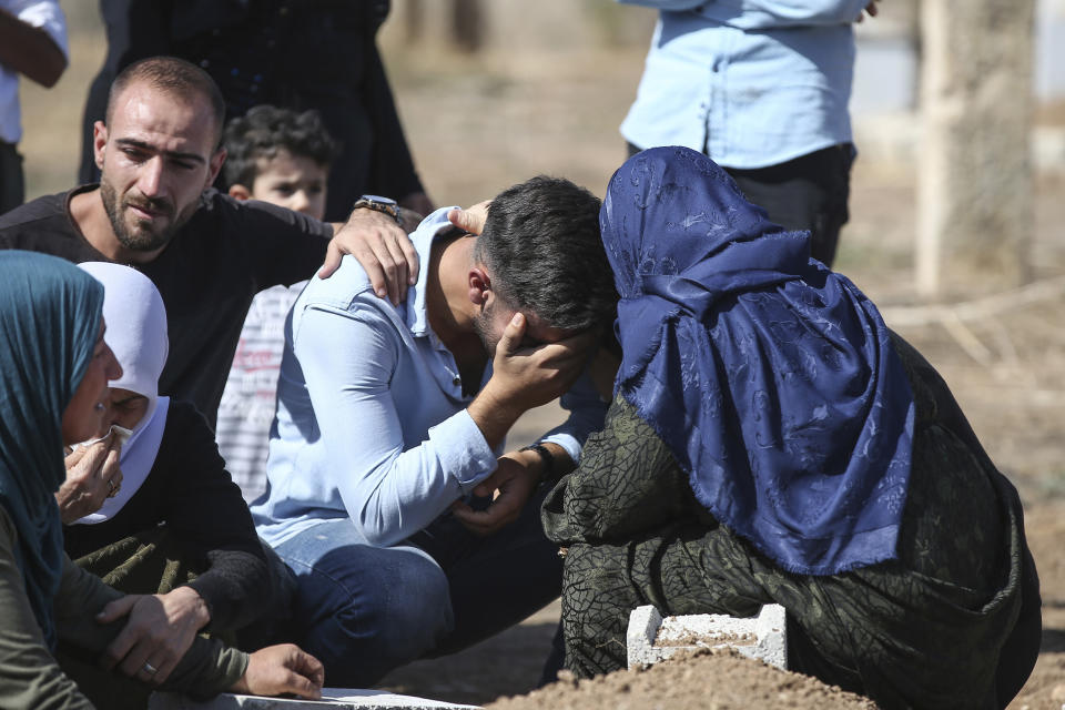 Relatives of Halil Yagmur, 64, who was killed Friday during mortar shelling from Syria, mourn over his grave at the cemetery in the town of Suruc, southeastern Turkey, at the border with Syria, Saturday, Oct. 12, 2019. Turkey says its military offensive has taken central Ras al-Ayn, a key border town in northeastern Syria, and its most significant gain since its cross-border operation began against Syrian Kurdish fighters began. (AP Photo/Emrah Gurel)