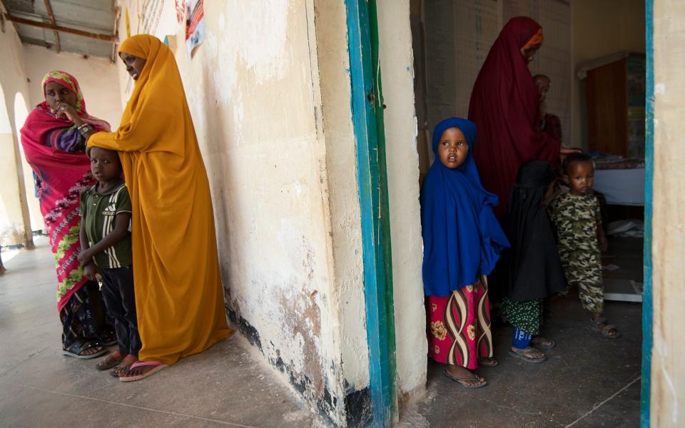 Women gather with their children at a health clinic in Ainabo to receive treatment for malnutrition - Eddie Mulholland