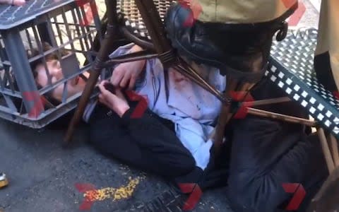 Screengrab taken with permission from a video issued by 7 News of a man being tackled with a milk crate and chairs by members of the public in Sydney - Credit: PA