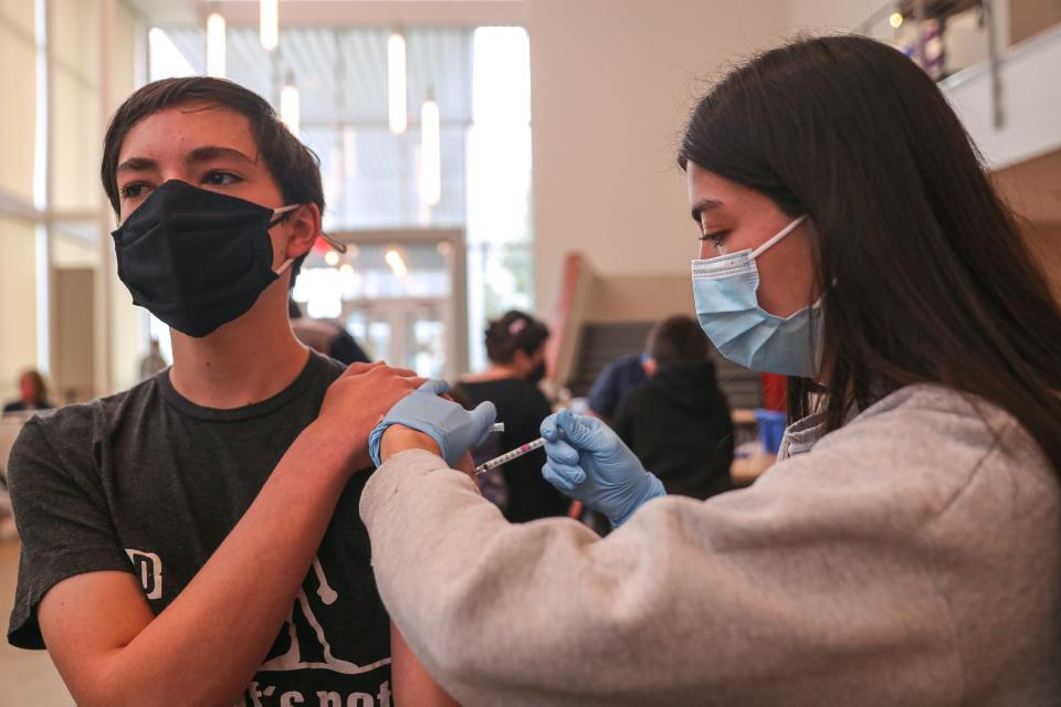 Vaccine administrator Isabella Grace injects a dose of the Pfizer COVID-19 vaccine into the arm of Diego Custard, 15, at a vaccine clinic for Austin school district families this month. Anyone 12 or older who is five months past a second mRNA vaccine should get a booster.