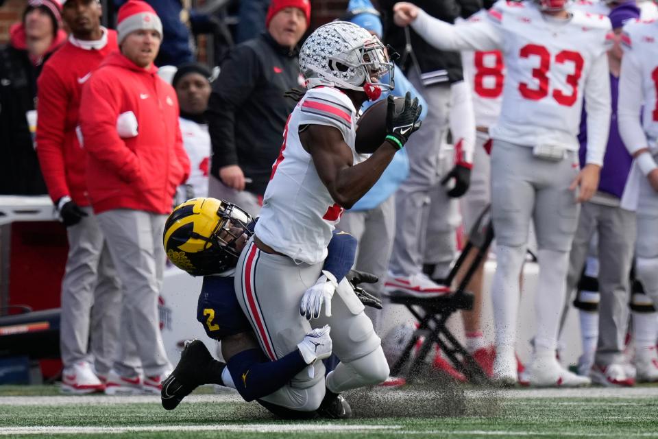 Ohio State receiver Marvin Harrison Jr. catches a pass while being defended by Michigan cornerback Will Johnson.