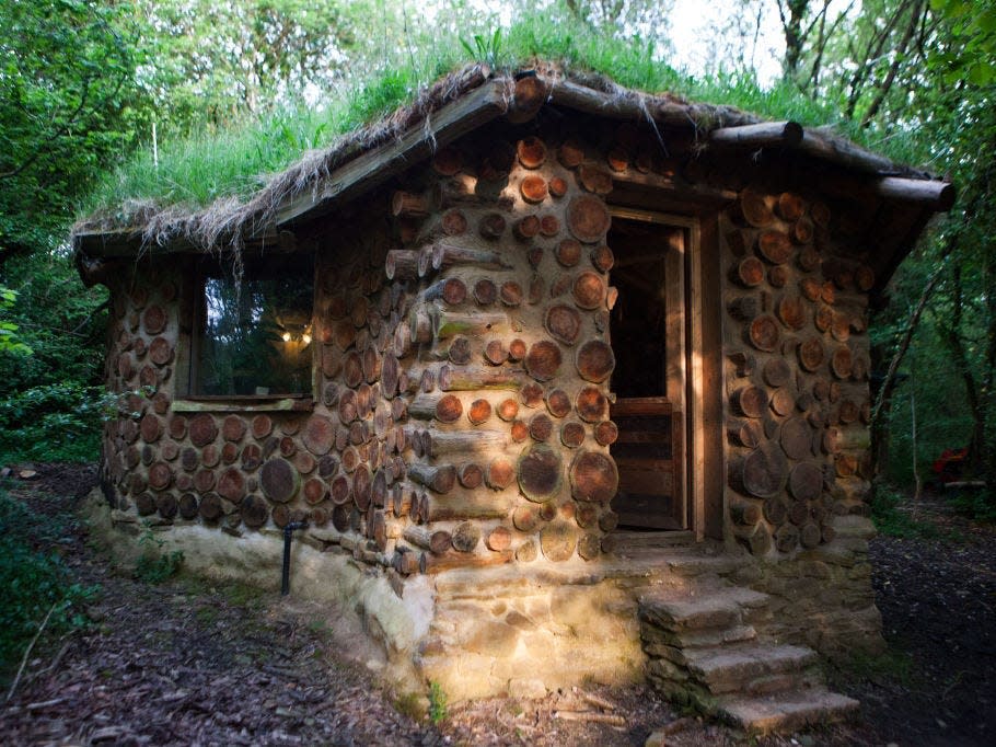 the exterior of the hobbit house, built with stones under a canopy of trees