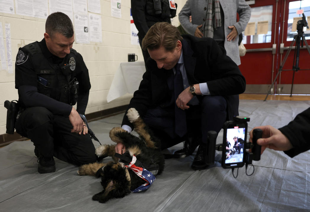 Democratic presidential candidate Rep. Dean Phillips plays with a police dog at Londonderry High School in New Hampshire .