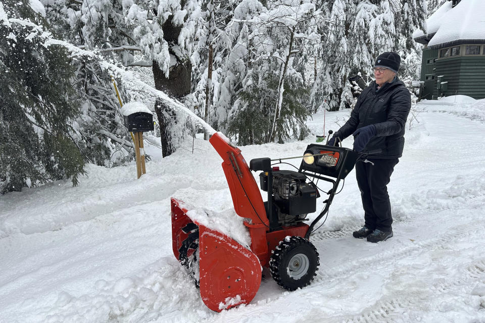 Betty Tidd, 78, clears snow Friday, April 5, 2024, in Gilford, N.H. Tidd lost power early Thursday but she and her husband have been staying comfortable thanks to their backup battery system and propane stove. (AP Photo/Nick Perry)