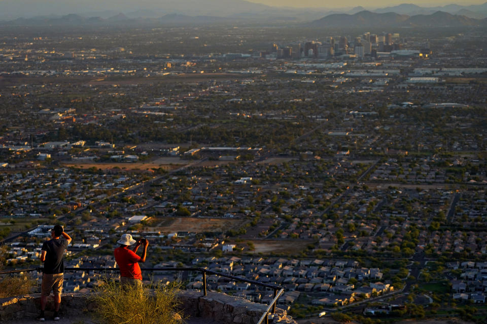 Hikers photograph the sun rising over Phoenix atop South Mountain, Monday, July 17, 2023. Phoenix is set to break its own record for consecutive days of highs of at least 110 degrees. Around one-third of Americans are under some type of heat advisory, with the most blistering temperatures in the South and West, where even the regular simmer has turned up a notch. (AP Photo/Matt York)