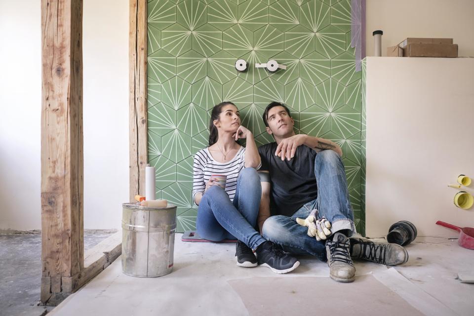 couple sitting on the floor of a bathroom being renovated