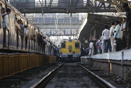 Commuters wait on a crowded railway platform as a train enters a suburban station in Mumbai February 12, 2014. REUTERS/Danish Siddiqui