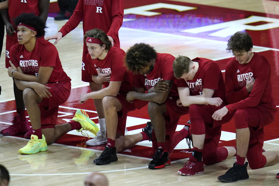 FILE - In this Dec. 14, 2020, file photo, members of the Rutgers men's basketball team take a knee during the playing of the national anthem prior to an NCAA college basketball game against Maryland in College Park, Md. The coronavirus, combined with the harsh spotlight that shined on racial inequality in the United States, further exposed the exploitative side of a system that relies heavily on Black football and basketball players to bring in the bucks. (AP Photo/Julio Cortez, File)