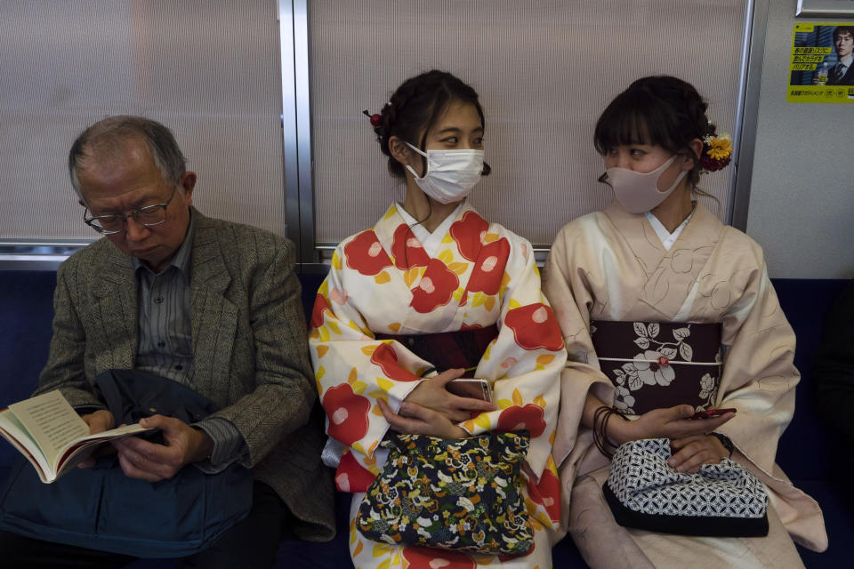 Two women wearing kimono chat in a train in Kyoto, Japan, March 18, 2020. Japanese tourism industry has taken a beating after Beijing banned group tours in late January. Japan's government restricted entry from China and South Korea in early March, then expanded the measures to parts of Europe. (AP Photo/Jae C. Hong)