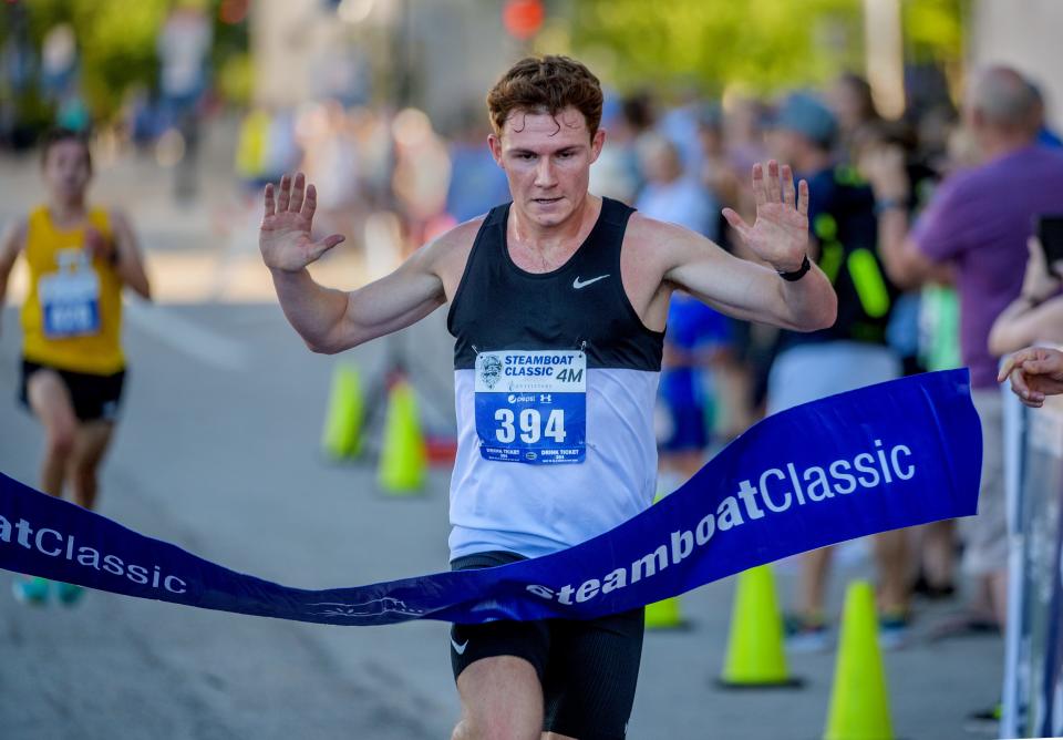 Tyler Owens of Springfield breaks the tape as the top finisher in the 2022 Steamboat Classic 4-mile race Saturday, June 18, 2022 in downtown Peoria. Owens finished the course with a time of 20:17.