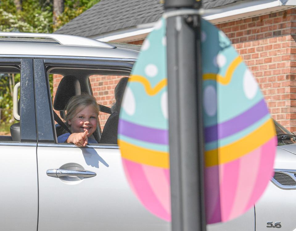 Dayton Wells of Anderson, S.C. points to a paper egg at Central Presbyterian Church in Anderson, visible as her mother Sunny Wells drives by during the drive-through Easter egg hunt in Anderson, April 9, 2020. Five churches each placed 12 laminated paper eggs visible from a car through Easter Sunday.